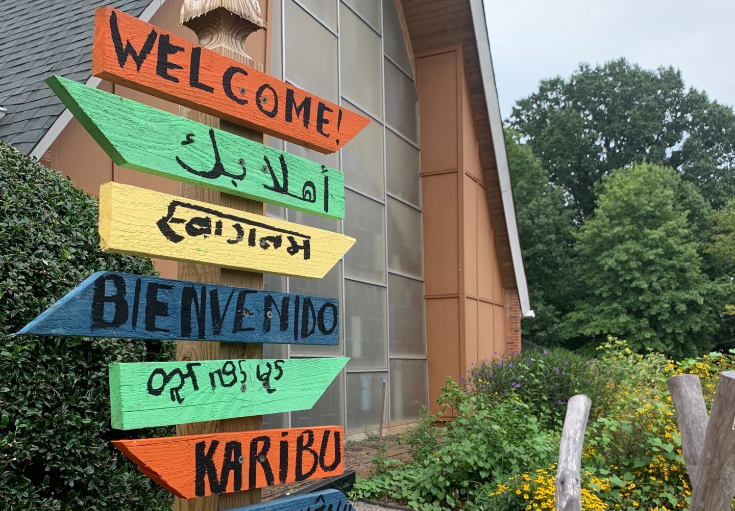 Painted sign that says "Welcome" in several languages