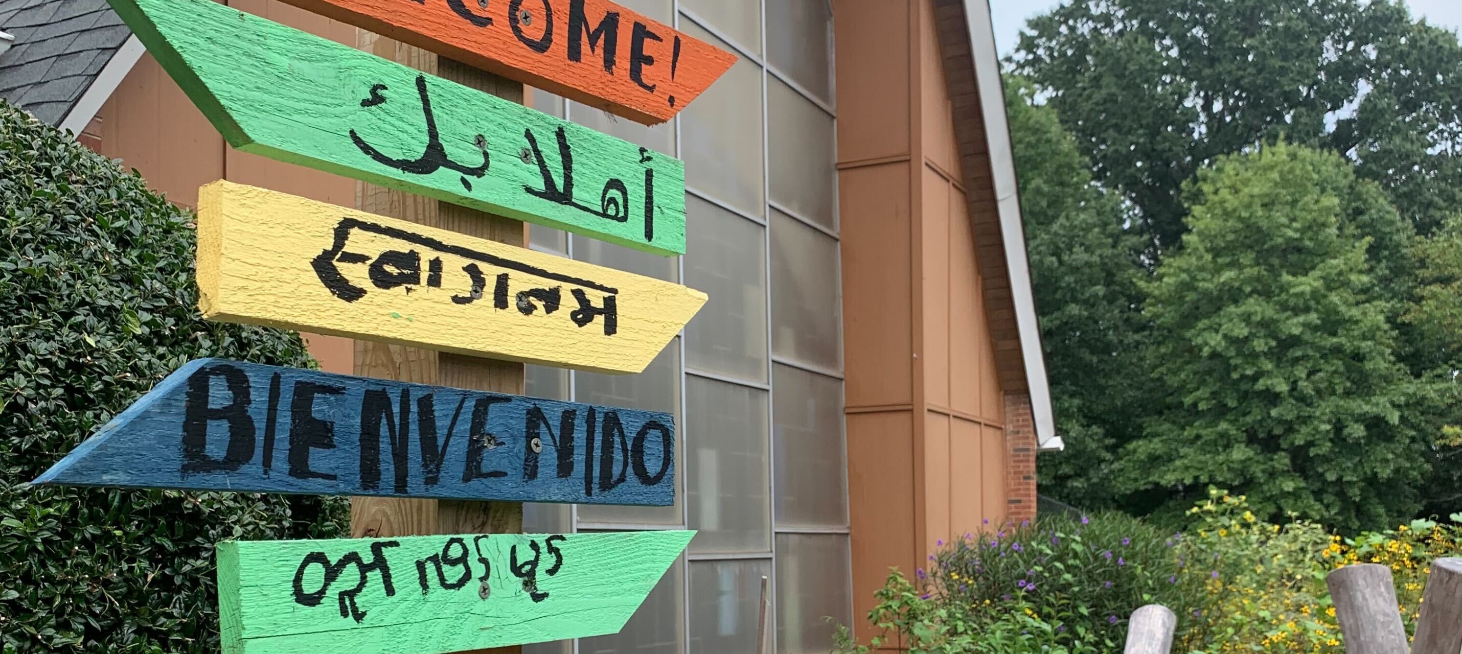 Painted sign that says "Welcome" in several languages