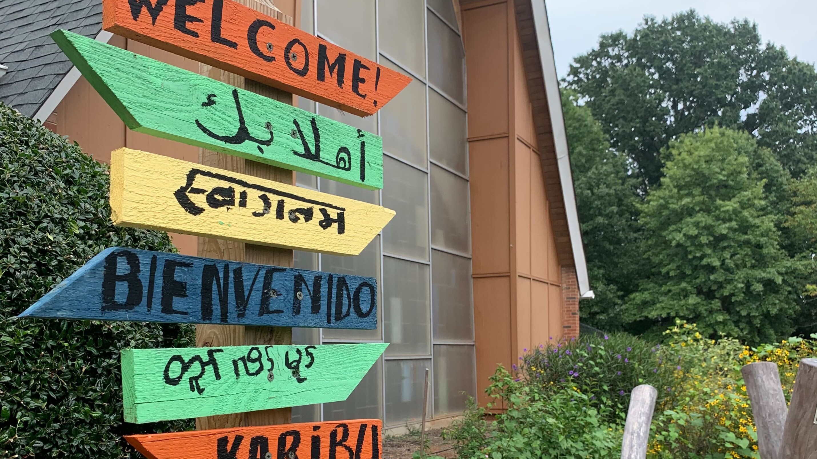 Painted sign that says "Welcome" in several languages