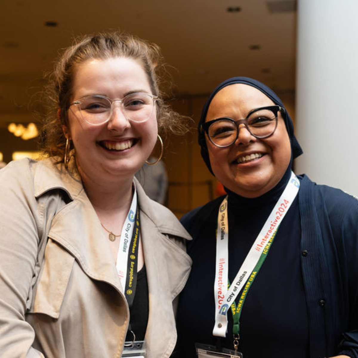 Two women attendees smile together at the Welcoming Interactive