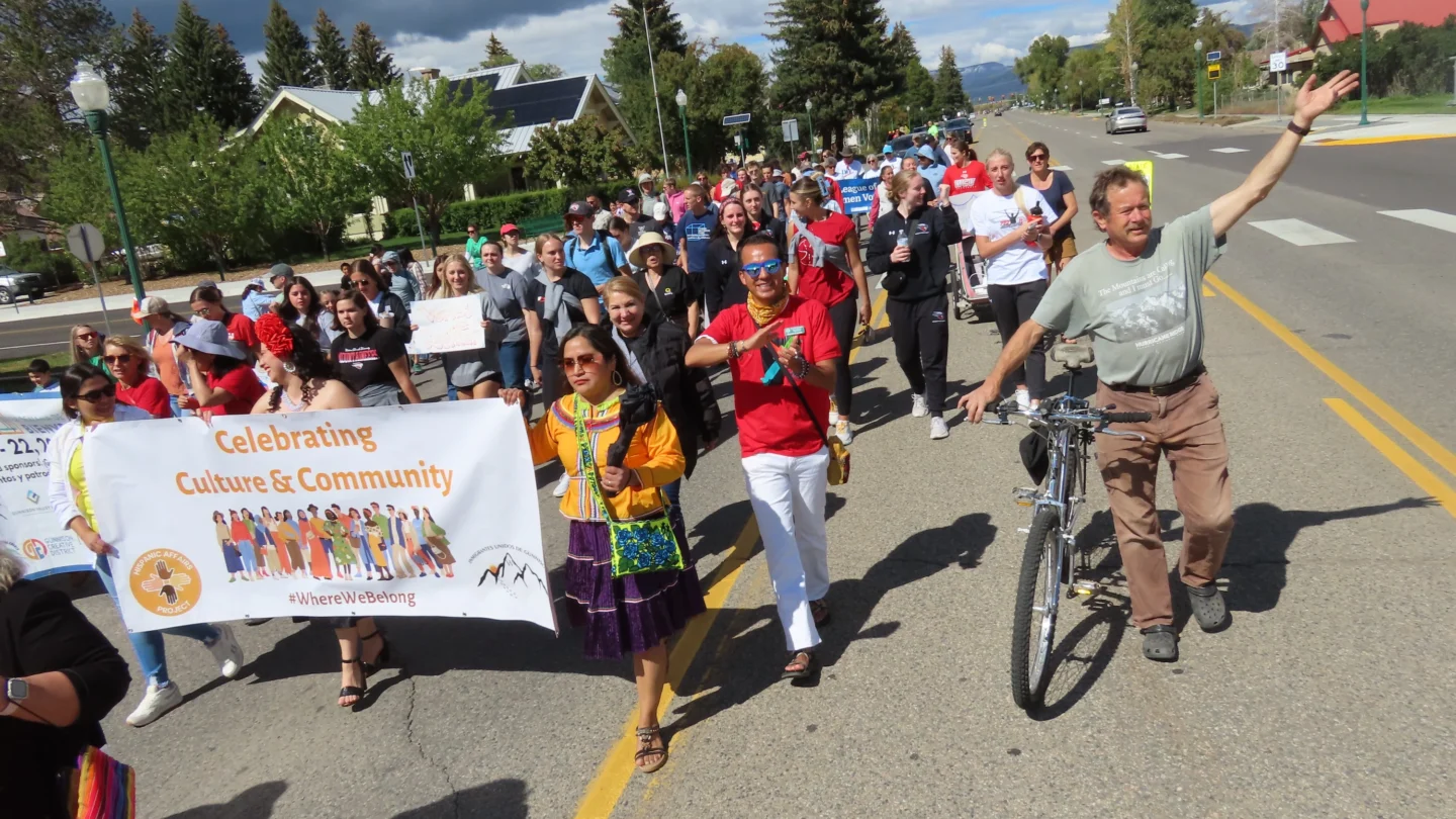 Group walks together through downtown Gunnison holding banners during the annual Diversity Walk during Welcoming Week 2024