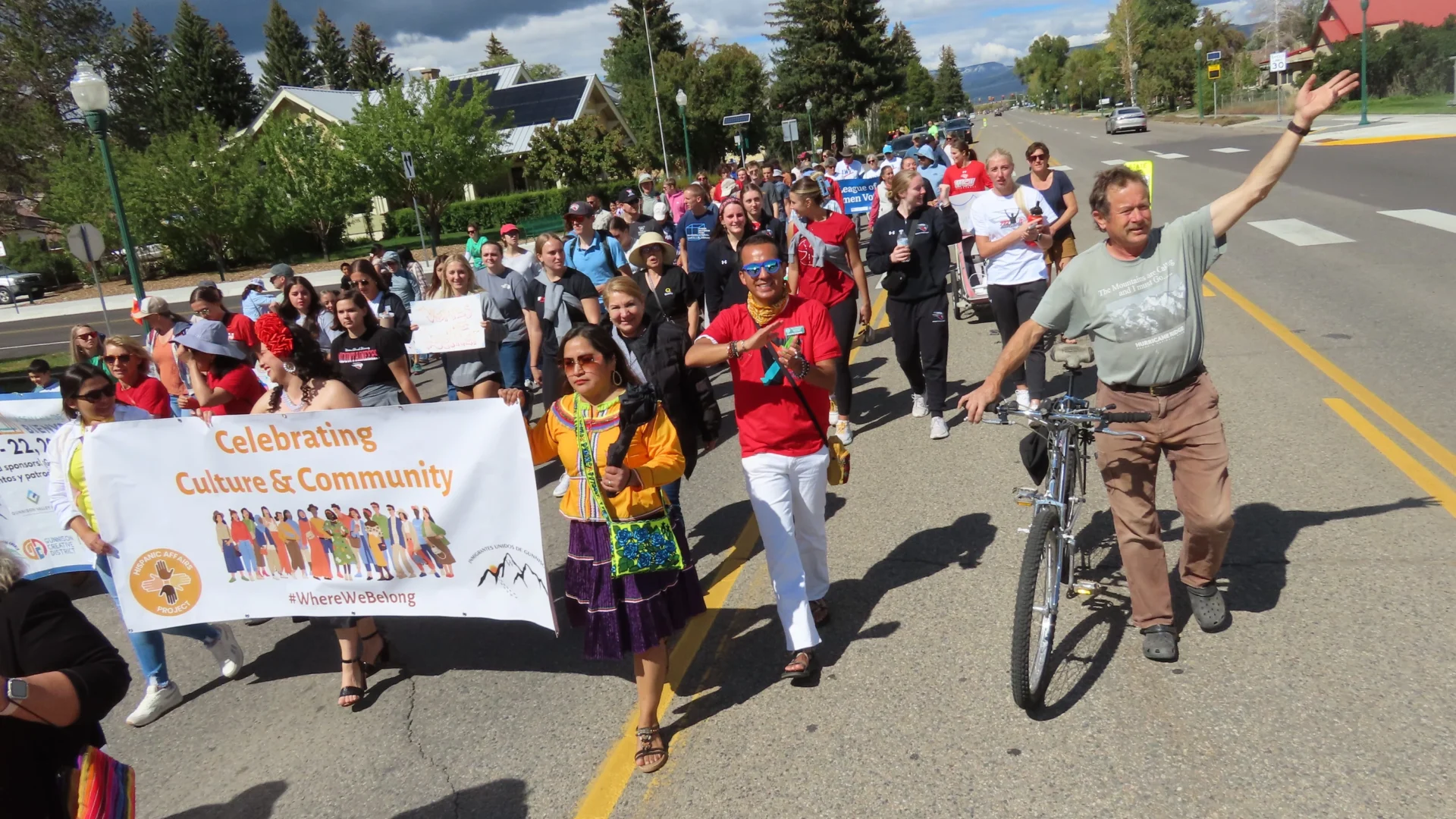 Group walks together through downtown Gunnison holding banners during the annual Diversity Walk during Welcoming Week 2024